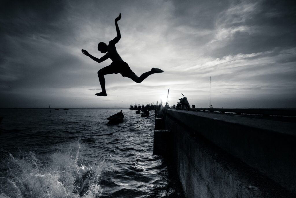 silhouette photography of man jumping on sea