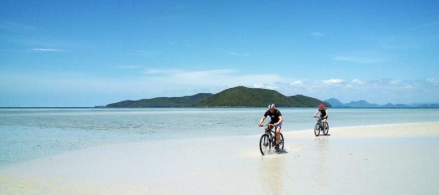 kaksi miestä pyöräilemässä rannalla